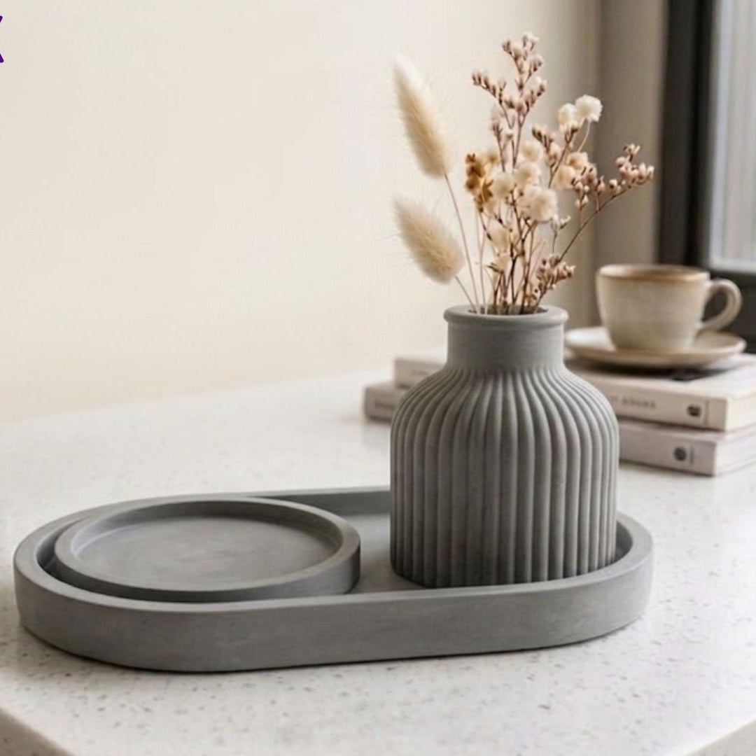 Gray ceramic vase with dried flowers on a matching tray on a table.